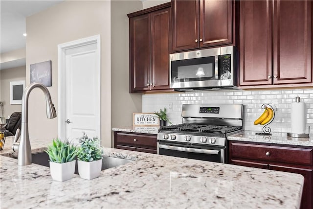 kitchen with light stone counters, stainless steel appliances, tasteful backsplash, and a sink