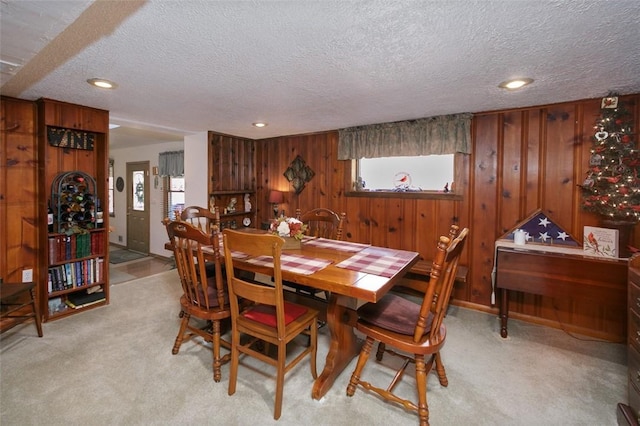 dining space featuring recessed lighting, light carpet, wooden walls, and a textured ceiling