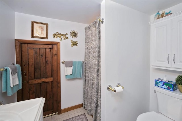 bathroom featuring tile patterned flooring, a shower with shower curtain, toilet, and baseboards