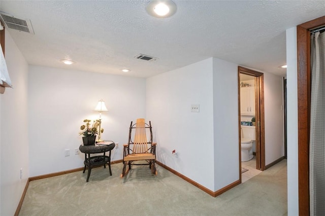 living area featuring visible vents, light colored carpet, baseboards, and a textured ceiling