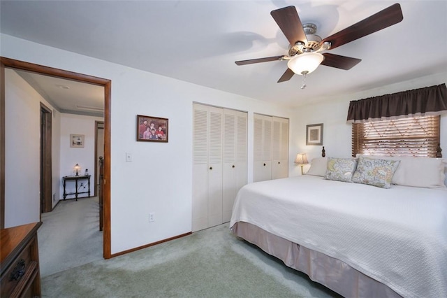 bedroom with baseboards, carpet floors, two closets, and a ceiling fan