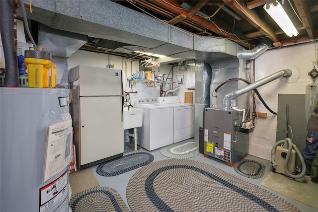 unfinished below grade area featuring independent washer and dryer, a sink, heating unit, electric water heater, and freestanding refrigerator