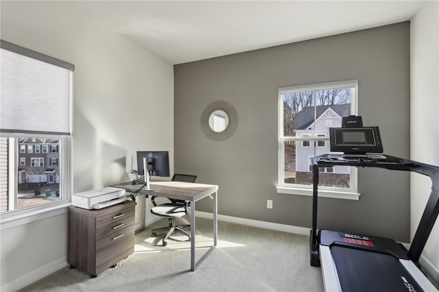 office area featuring baseboards and light carpet