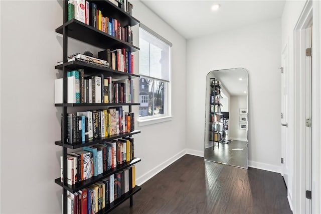 corridor with baseboards and wood finished floors