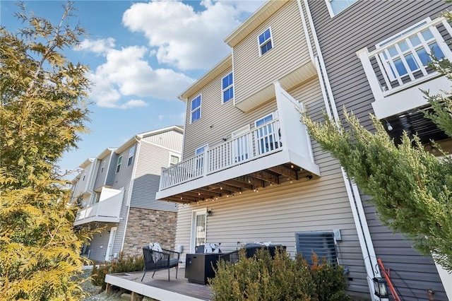 back of property with central AC unit and a deck