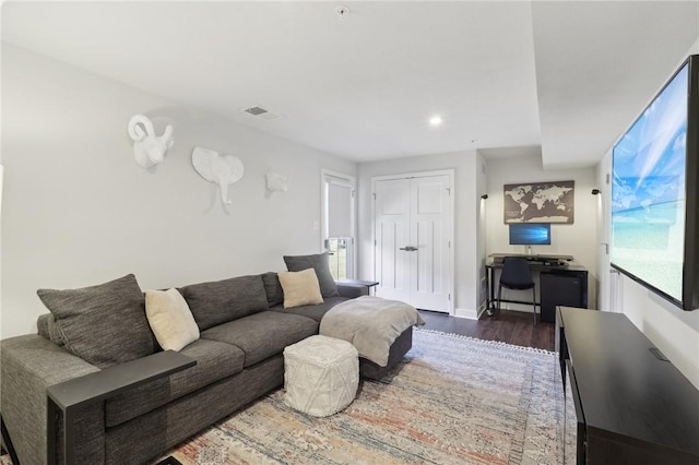 living room featuring wood finished floors, visible vents, and baseboards