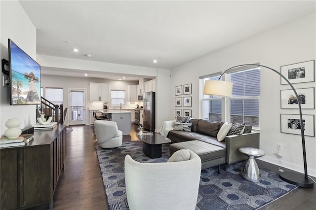 living area with dark wood finished floors, recessed lighting, stairs, and baseboards