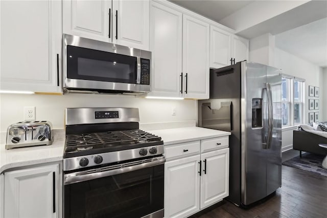 kitchen with light stone counters, appliances with stainless steel finishes, white cabinets, and dark wood-style flooring