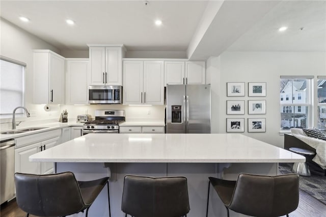 kitchen with a sink, stainless steel appliances, a wealth of natural light, and white cabinets