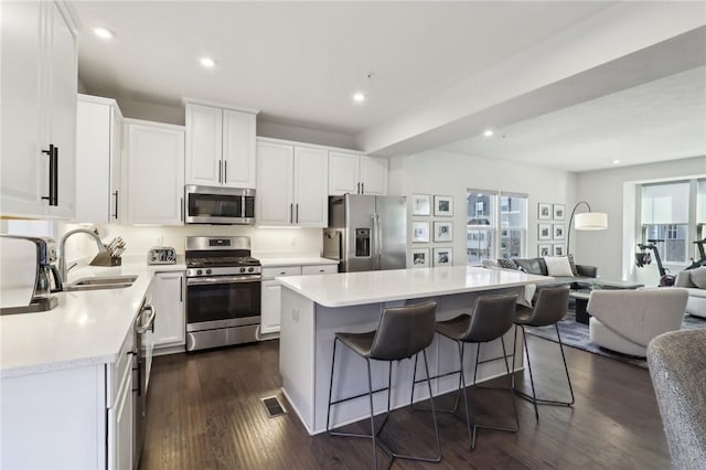 kitchen featuring visible vents, a sink, open floor plan, dark wood-style floors, and stainless steel appliances