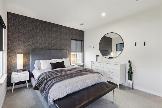 bedroom featuring visible vents, baseboards, recessed lighting, light carpet, and an accent wall