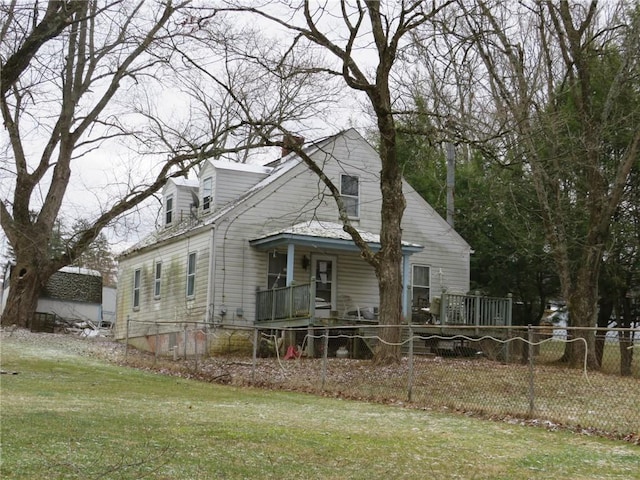 view of front facade with a chimney, a front yard, and fence