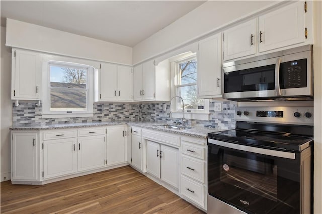 kitchen with a sink, tasteful backsplash, appliances with stainless steel finishes, and white cabinetry