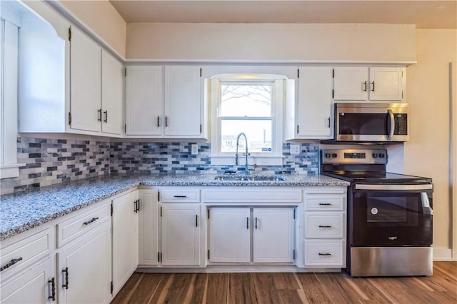 kitchen with backsplash, white cabinets, appliances with stainless steel finishes, and a sink