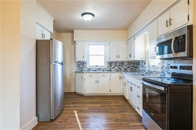 kitchen with dark wood finished floors, a sink, decorative backsplash, stainless steel appliances, and white cabinets