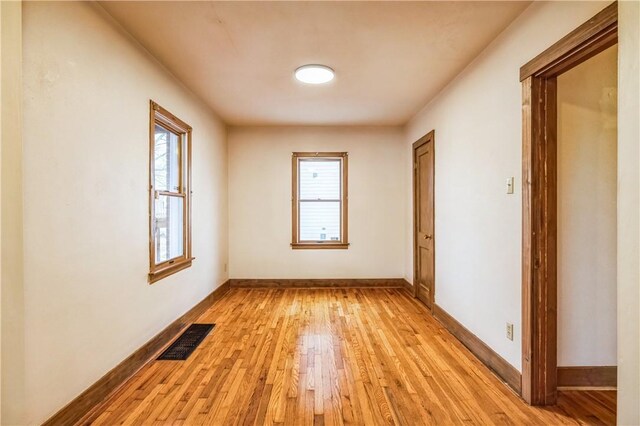 spare room with light wood-type flooring, visible vents, plenty of natural light, and baseboards