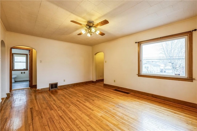 unfurnished room featuring visible vents, arched walkways, a ceiling fan, and light wood finished floors