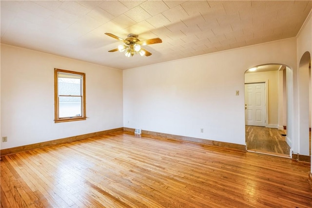 spare room with visible vents, baseboards, arched walkways, ceiling fan, and hardwood / wood-style flooring