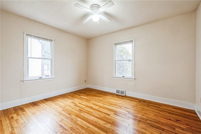 empty room featuring visible vents, a ceiling fan, baseboards, and wood-type flooring