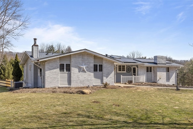 exterior space featuring a lawn, covered porch, brick siding, solar panels, and a chimney