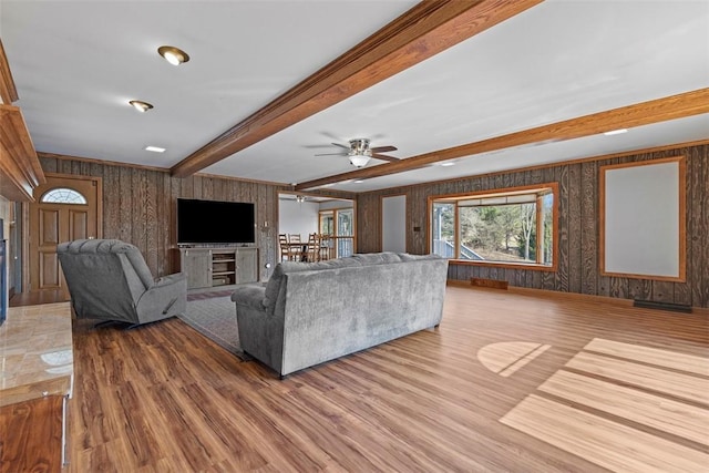 unfurnished living room with ceiling fan, beam ceiling, and wood finished floors