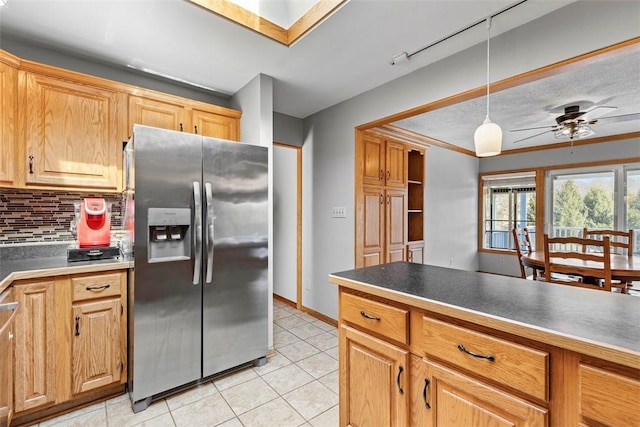 kitchen with a ceiling fan, light tile patterned flooring, stainless steel refrigerator with ice dispenser, decorative light fixtures, and tasteful backsplash