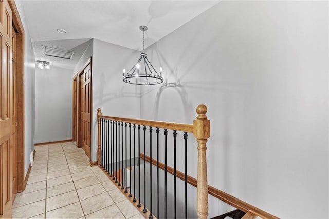 corridor with visible vents, baseboards, a chandelier, light tile patterned floors, and an upstairs landing