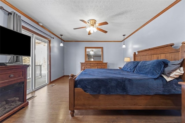 bedroom with wood finished floors, baseboards, a textured ceiling, crown molding, and access to outside