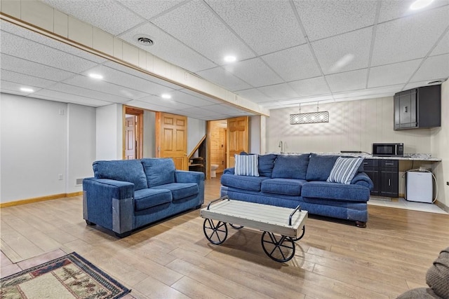 living area with visible vents, baseboards, light wood-style flooring, and stairs