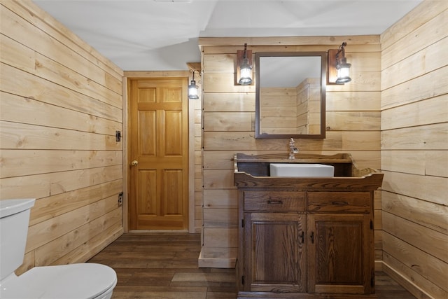 bathroom featuring vanity, toilet, wood finished floors, and wood walls