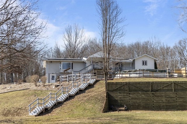 rear view of house with stairway, a wooden deck, and fence