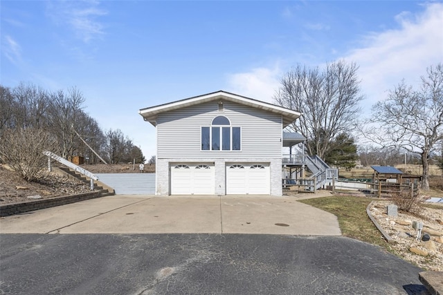 view of home's exterior with an attached garage, concrete driveway, and stairs