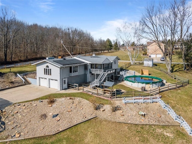 rear view of house with stairway, driveway, an attached garage, and fence