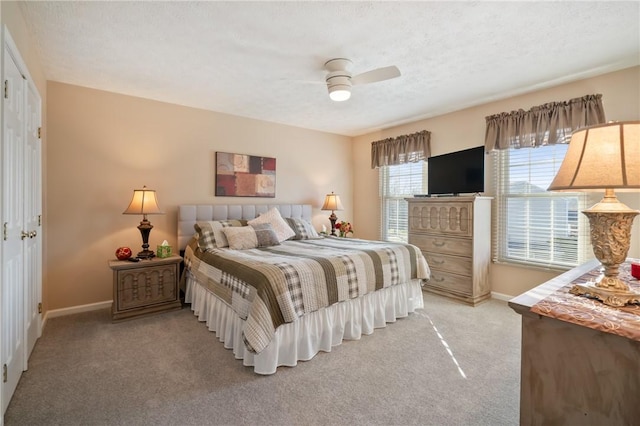 bedroom featuring light colored carpet, a textured ceiling, baseboards, and ceiling fan