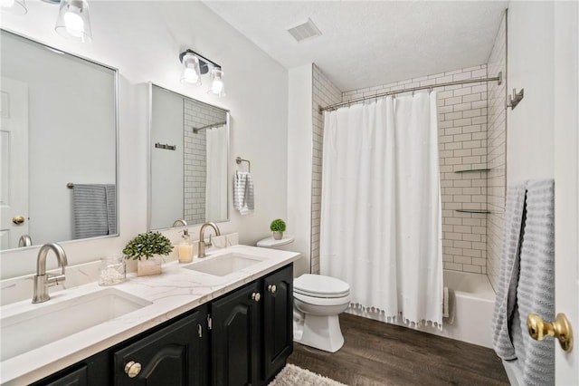 bathroom with double vanity, toilet, wood finished floors, and a sink