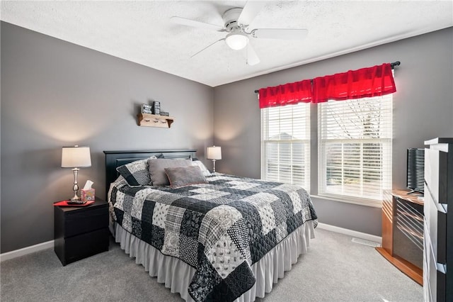 bedroom featuring light carpet, a textured ceiling, baseboards, and a ceiling fan