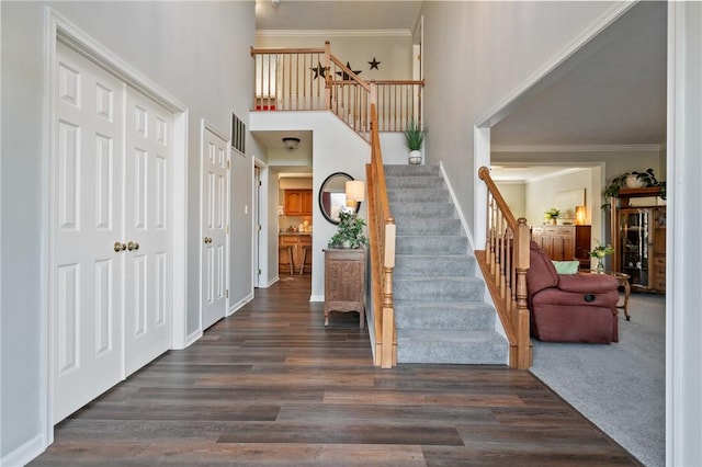 entryway with stairs, crown molding, a high ceiling, and wood finished floors