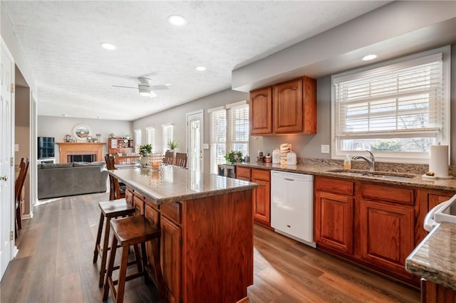 kitchen featuring dishwasher, wood finished floors, brown cabinetry, a ceiling fan, and a sink