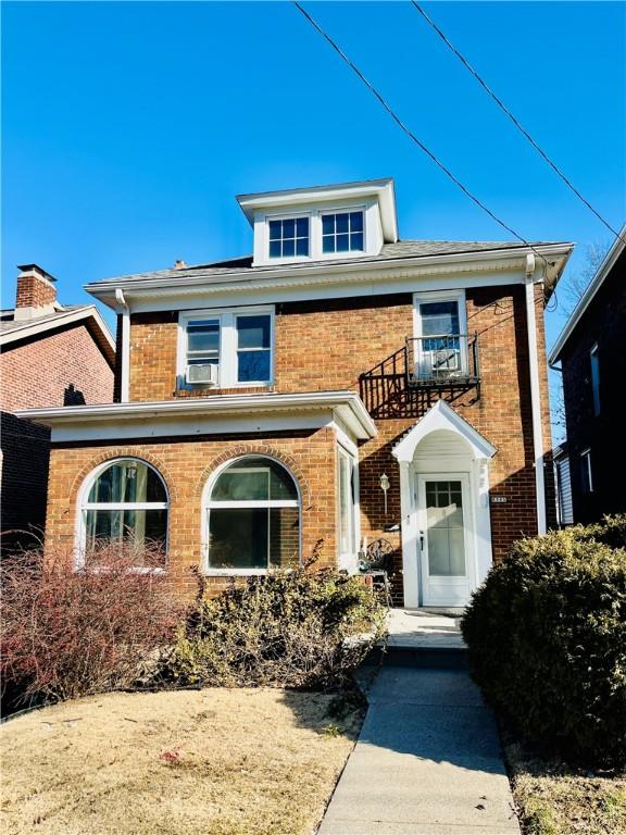 traditional style home with brick siding, cooling unit, and a balcony