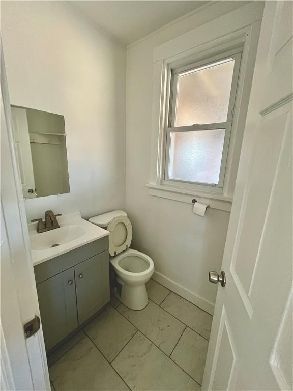 half bathroom featuring toilet, vanity, and baseboards