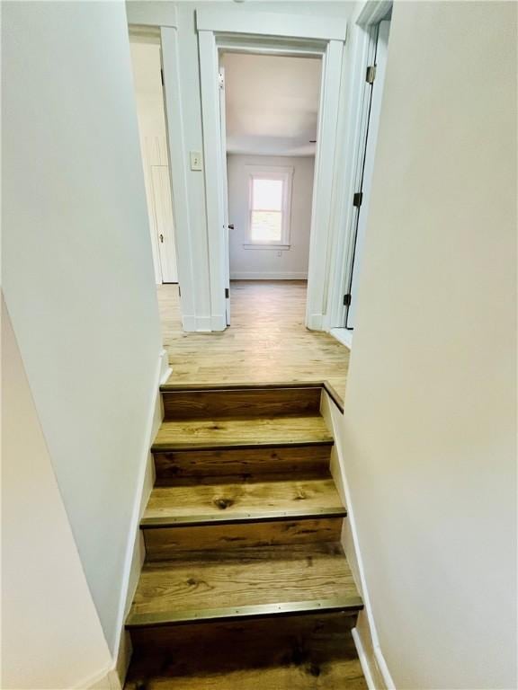 stairway with wood finished floors and baseboards