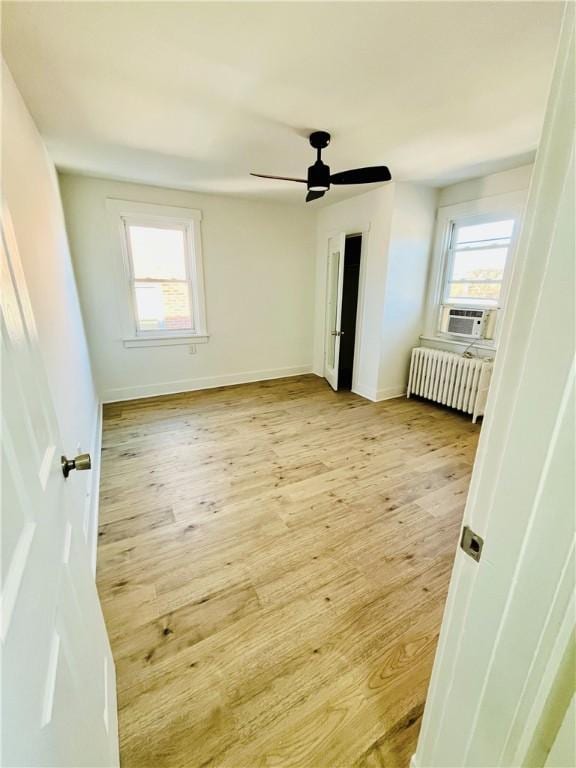 unfurnished bedroom featuring light wood finished floors, multiple windows, and radiator