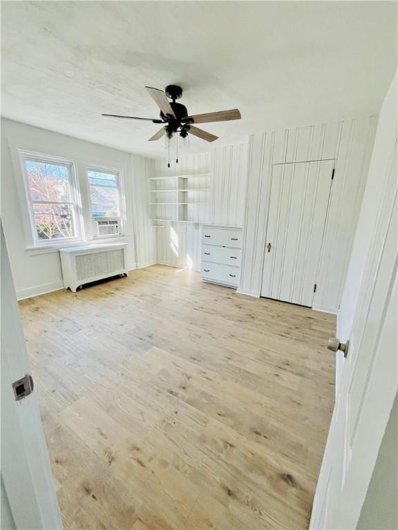 unfurnished bedroom with a ceiling fan, radiator heating unit, and light wood-style floors