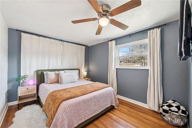 bedroom featuring ceiling fan, baseboards, and wood finished floors