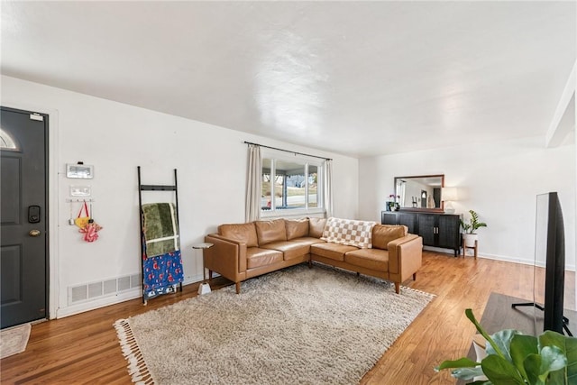 living area with baseboards, visible vents, and light wood finished floors