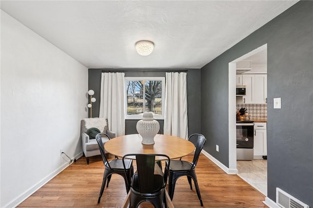 dining room with visible vents, baseboards, and light wood-style floors