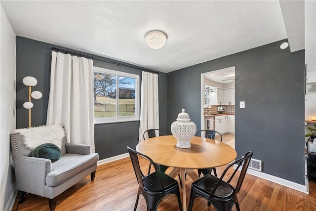 dining area featuring light wood finished floors, visible vents, and baseboards