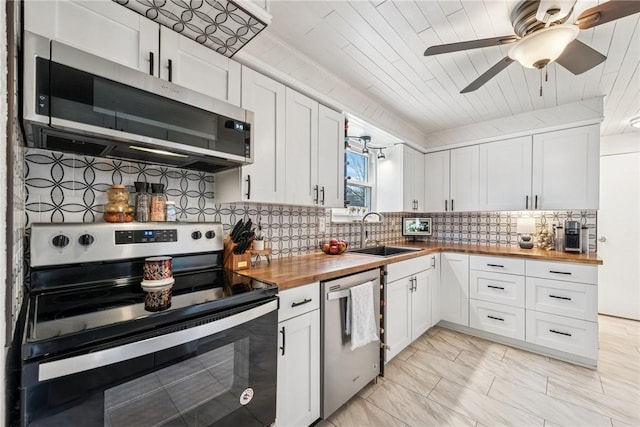 kitchen with wooden counters, a sink, decorative backsplash, appliances with stainless steel finishes, and white cabinetry