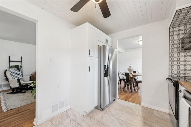 kitchen featuring wood ceiling, white cabinets, visible vents, and stainless steel fridge