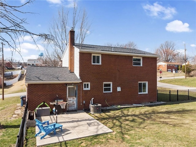 rear view of property with central air condition unit, fence, a yard, brick siding, and a patio area